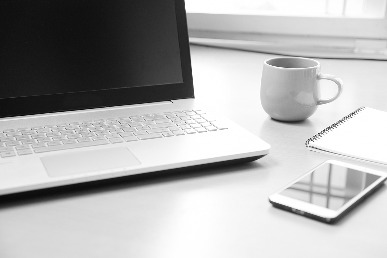 smartphone notebook paper for note message and a cup of coffee on wood desk background soft focus black and white photo
